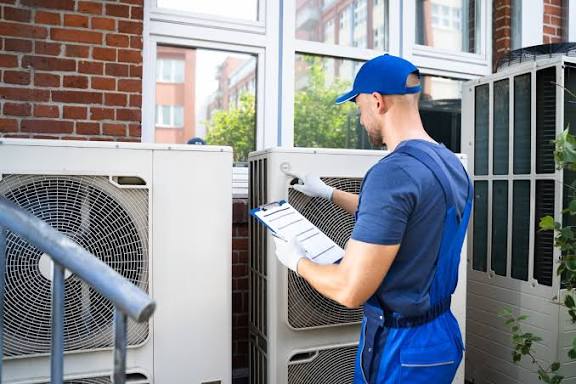 HVAC technician inspecting multiple outdoor air conditioning units