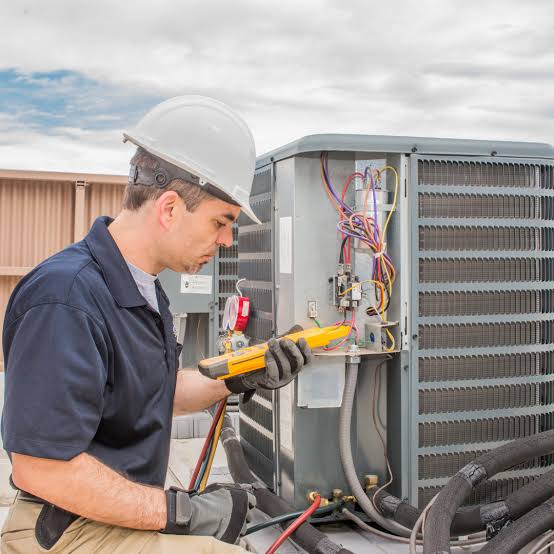 HVAC technician using a diagnostic meter on an outdoor condenser