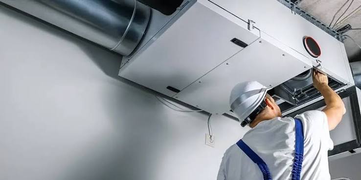 HVAC technician working on a ceiling-mounted ventilation system