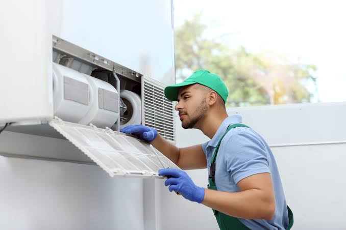 HVAC technician servicing an indoor wall-mounted air conditioning unit