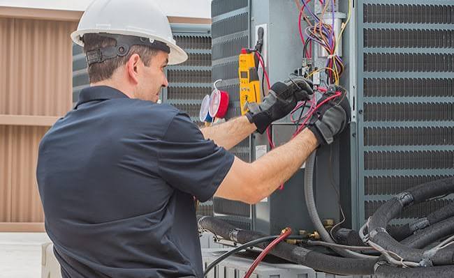 HVAC technician repairing controls inside a rooftop system